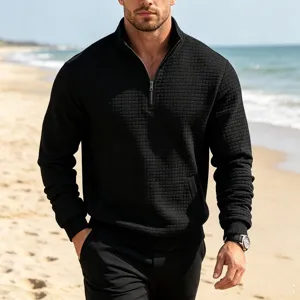 Detail view of black waffle knit quarter zip mock neck sweatshirt shown on beach background.