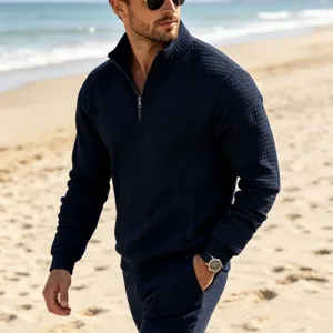 Detail view of men's dark blue quarter-zip waffle knit sweatshirt on beach setting.