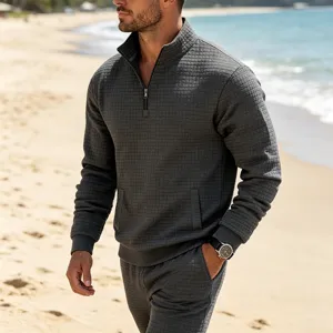 Detailed view of men's jacquard grid quarter-zip sweatshirt, textured fabric, beach scene.