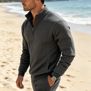 Detail shot of men grey waffle knit stand collar quarter zip pullover on beach backdrop.