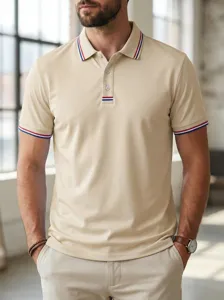 Men short sleeve polo shirt detail view, beige knit fabric with blue and red stripe trim collar.