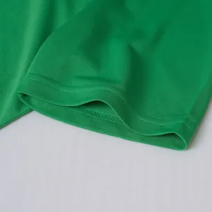 Gros plan du détail de la manchette de polo respirante en maille verte avec des coutures fines.