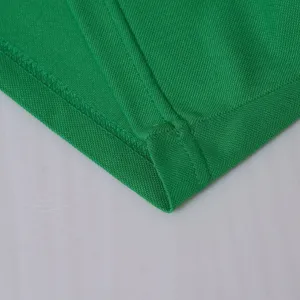 Detail du tissu polo vert montrant une texture maille respirante et des coutures.