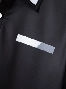 Men's black polo shirt detail, contrast collar and chest geometric stripe design, breathable fabric.
