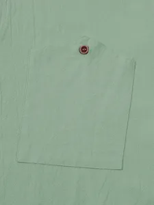 Close-up detail of mens green linen shirt pocket with button, casual summer beach top view.