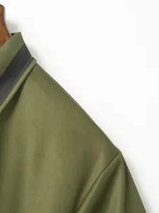 Detail shot of men's polo shirt collar, green fabric, textured weave, stylish lapel trim.