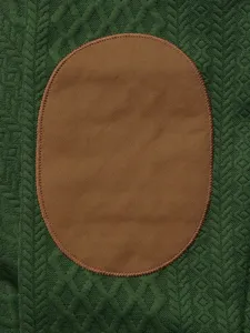Men green jacquard knit sweater detail close up showing classic brown elbow patch texture.