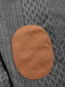 Detailed view of men's knit sweater featuring jacquard texture and elbow patch design.