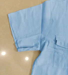 Vista detallada de camisa de manga corta de lino azul claro con bolsillo en el pecho