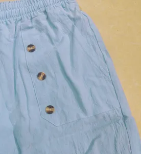 Close-up detail of light blue mens casual linen pants featuring pocket and buttons.