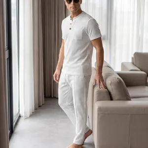 Detailed view of men's white waffle knit short sleeve top and casual pants set in room.