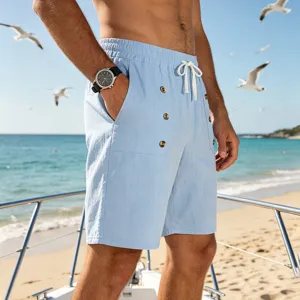 Close-up detail of men's light blue linen summer cargo shorts with drawstring on beach background.