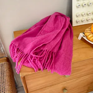 Morbida sciarpa rosa con frange in misto lana esposta in ambiente accogliente per autunno inverno.
