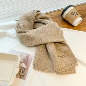 Detail view of the warm knitted scarf texture, soft fabric close-up, cozy autumn winter style.