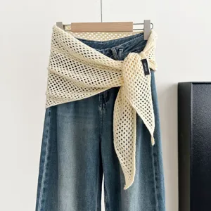 Detail view of cream hollow knit triangular shawl scarf paired with blue denim pants, stylish.