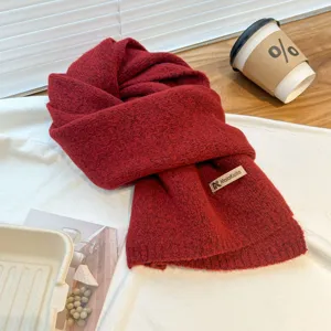 Detailed view of the cozy red knit scarf, showing soft woolen texture and label.