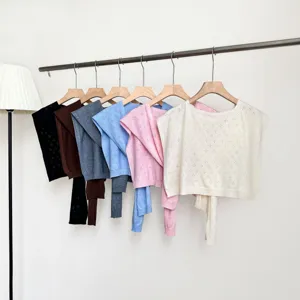 Detailed view of hollow knit short sleeve tops hanging neatly in multiple colors.