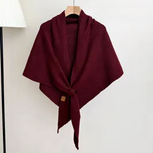 Detail van bordeaux gebreide omslagdoek, gezellige wintersjaal hangend aan houten hanger.