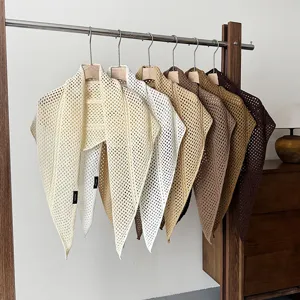 Detailed view of hollow knit triangular shawls hanging nicely in various neutral colors.