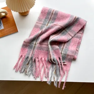 Detailed view of cozy pink and grey plaid winter scarf with soft tassel fringe texture.