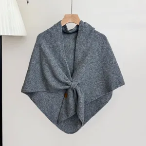 Gedetailleerd overzicht van de grijze gebreide sjaaltextuur met knoop, warm winteraccessoire.