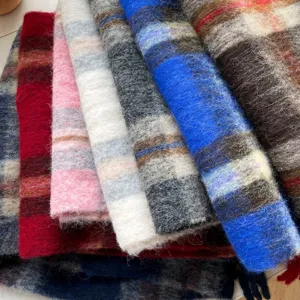Detailed close-up of soft cozy winter plaid fuzzy tassel scarves in various vibrant colors.