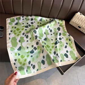 Detailed view of a green leopard print silk square scarf, perfect for neckwear or chic styling.