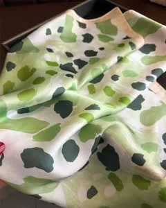 Detailed closeup view of a green abstract printed silk square scarf, perfect for stylish neck wear.