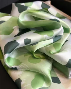 Detailed close-up of a green abstract pattern imitation silk square scarf, soft and smooth.