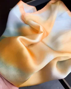 Detailed close-up of the smooth gradient silk scarf showing soft fabric folds and tones.