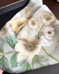 Close-up detail of a elegant green floral print silk scarf, showing soft smooth fabric texture.