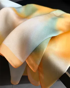 Close-up detail of artistic gradient silk scarf showing soft fabric texture and elegant color.