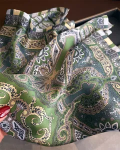 Detailed view of vintage green paisley silk square scarf, elegant retro pattern print texture.