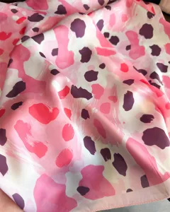 Silk scarf fabric detail, pink abstract leopard print pattern, soft texture close up view.