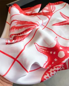 Detail view of red starfish print silk square scarf, resort style sun protection neck wrap for women.