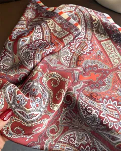 Close-up detail of vintage paisley silk square scarf showing rich red texture and print.