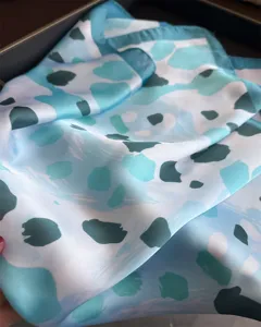 Blue abstract print silk scarf detail, soft fabric texture close up view, elegant neckerchief.
