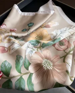 Close-up detail of beige floral printed silk scarf showing elegant vintage flower pattern.