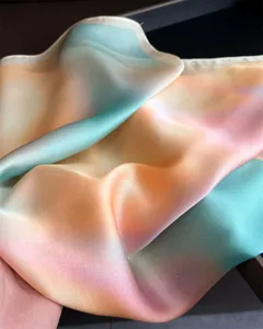 Close-up detail of women's gradient silk square scarf, soft pastel colors and smooth drape.