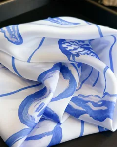 Closeup of blue and white abstract printed silk scarf showing fine fabric texture and draping.