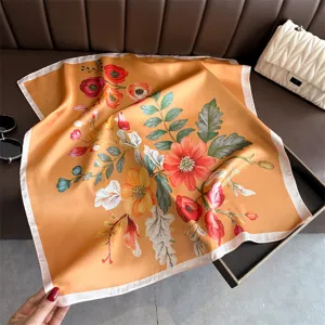 Detailed view of floral print silk square scarf, elegant botanical pattern on orange base.