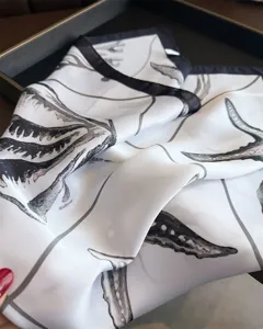 Detailed close-up shot of a black and white printed silk scarf, soft texture, elegant design.
