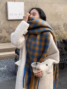 Detailed view of the cozy blue and yellow plaid scarf with fringes, perfect for winter style.