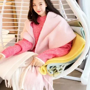 Close-up detail of the cozy pink mohair large scarf worn by a model in a hanging chair.