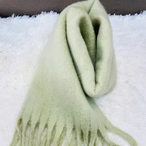 Detailed shot of the soft mint green fluffy mohair scarf texture, thick winter tassel knit.