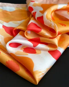 Close-up detail shot of elegant abstract leopard print silk scarf showing soft fabric folds.