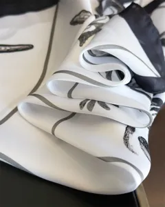 Detailed close-up of a white silk scarf featuring elegant black and grey abstract floral print.