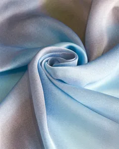 Close-up detail of smooth gradient blue silk fabric showing elegant drape and texture.