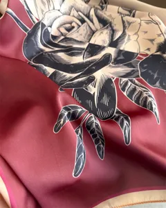 Close-up of women's fashion silk scarf with contrast rose print and smooth satin texture.