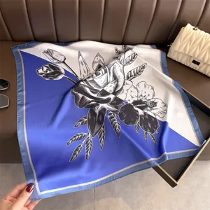 Detail shot of a blue and white colorblock silk square scarf featuring elegant floral print.
